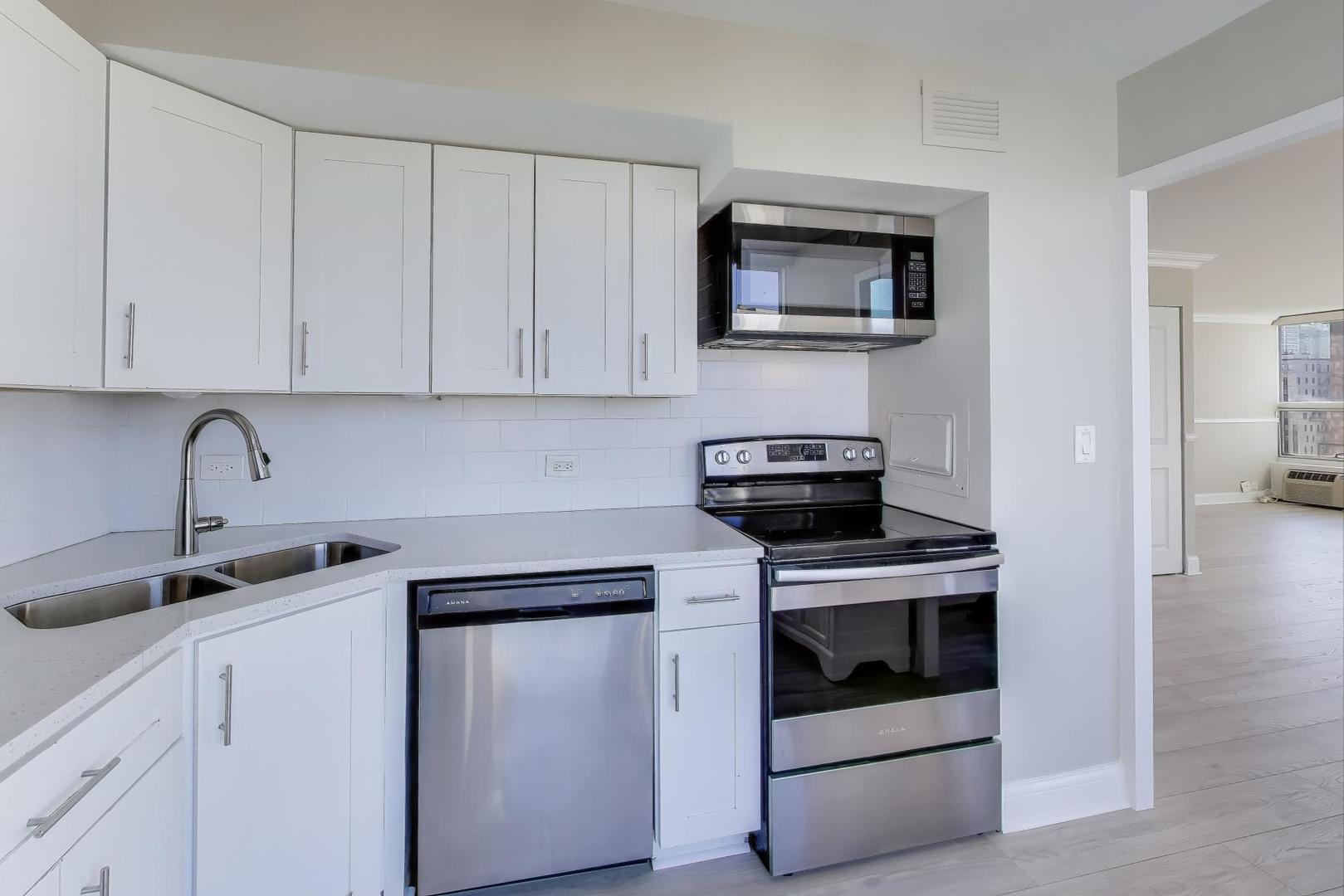 1400 North State Parkway, Unit 18A Chicago, IL 60610 - Photo 9 of 31 a kitchen with white cabinets and stainless steel appliances