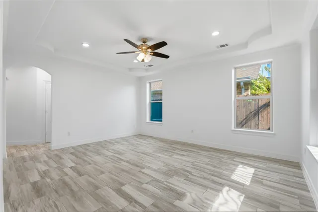 a view of empty room with wooden floor and fan