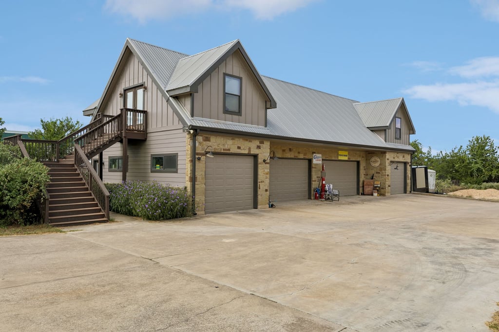 10111 Signal Hill Road Austin, TX 78737 - Photo 31 of 40 An expansive concrete driveway leads to a multi-car garage with stone veneer details.