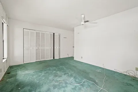 an empty room with a ceiling fan and carpet