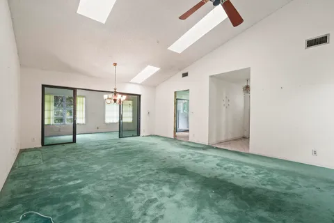 a view of an empty room with window and chandelier fan