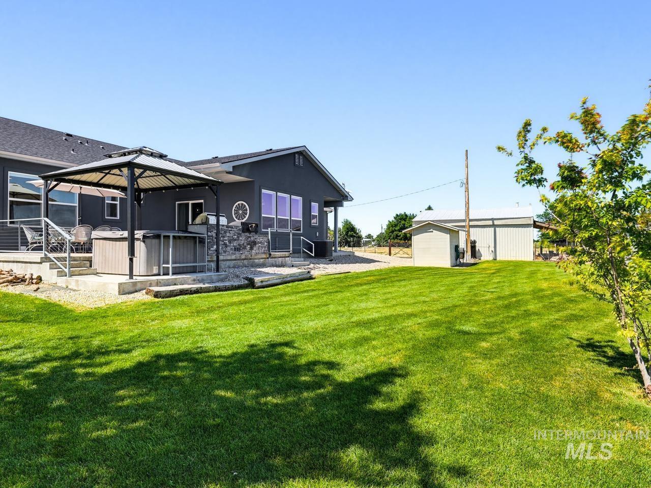 4950 West Columbia Road Nampa, ID 83687 - Photo 44 of 50 Spacious green lawn with a dark-colored exterior structure featuring a covered patio, outdoor decking, and a built-in outdoor cooking area