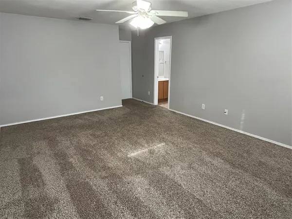a view of an empty room with a chandelier fan