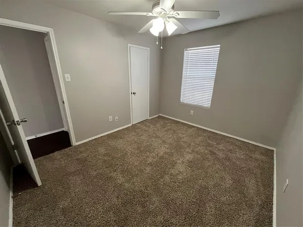 an empty room with windows and fan