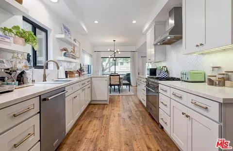 a large kitchen with stainless steel appliances granite countertop a lot of counter space and wooden floors