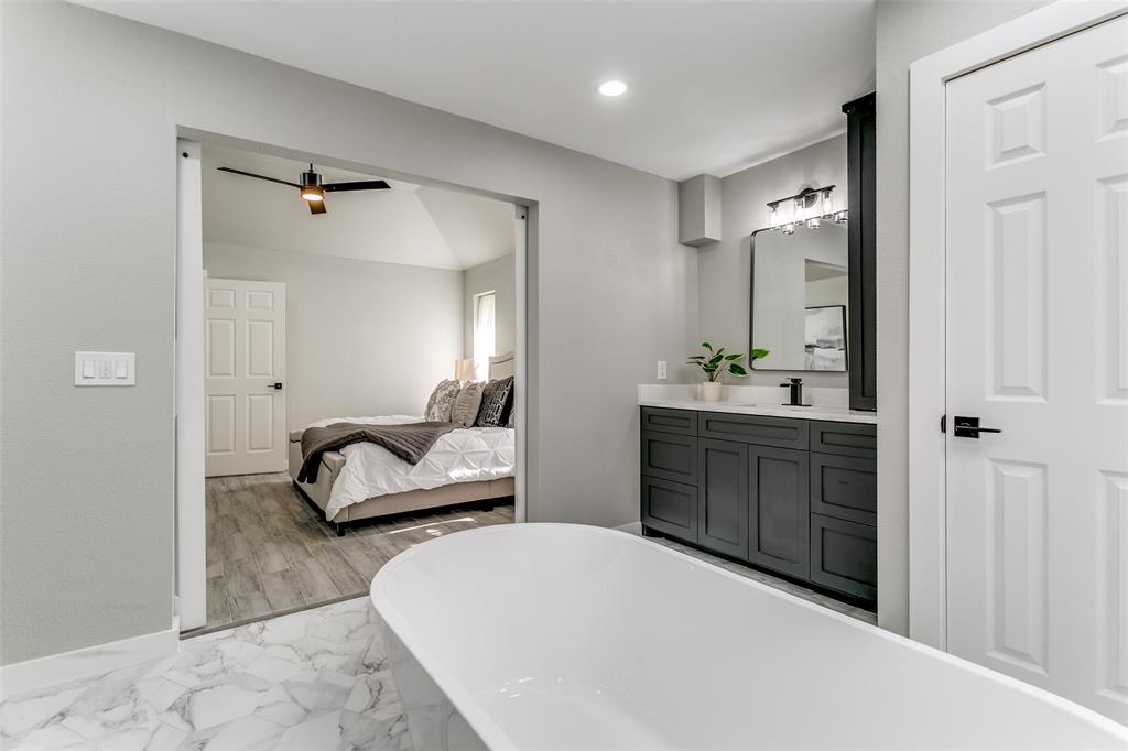 3913 Bobbin Lane Addison, TX 75001 - Photo 15 of 23 Ensuite bathroom with vanity, a freestanding bath, light marble finish floors, and recessed lighting
