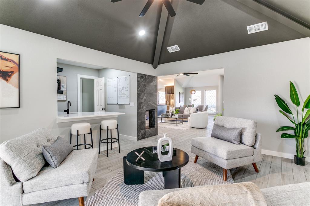 3913 Bobbin Lane Addison, TX 75001 - Photo 5 of 23 Living room featuring light wood finished floors, ceiling fan, vaulted ceiling, and a fireplace
