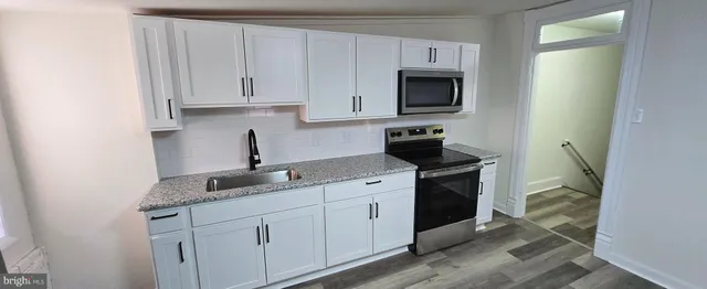 a kitchen with granite countertop white cabinets and stainless steel appliances