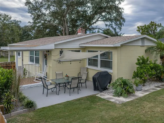 a view of a patio with table and chairs potted plants and a large tree