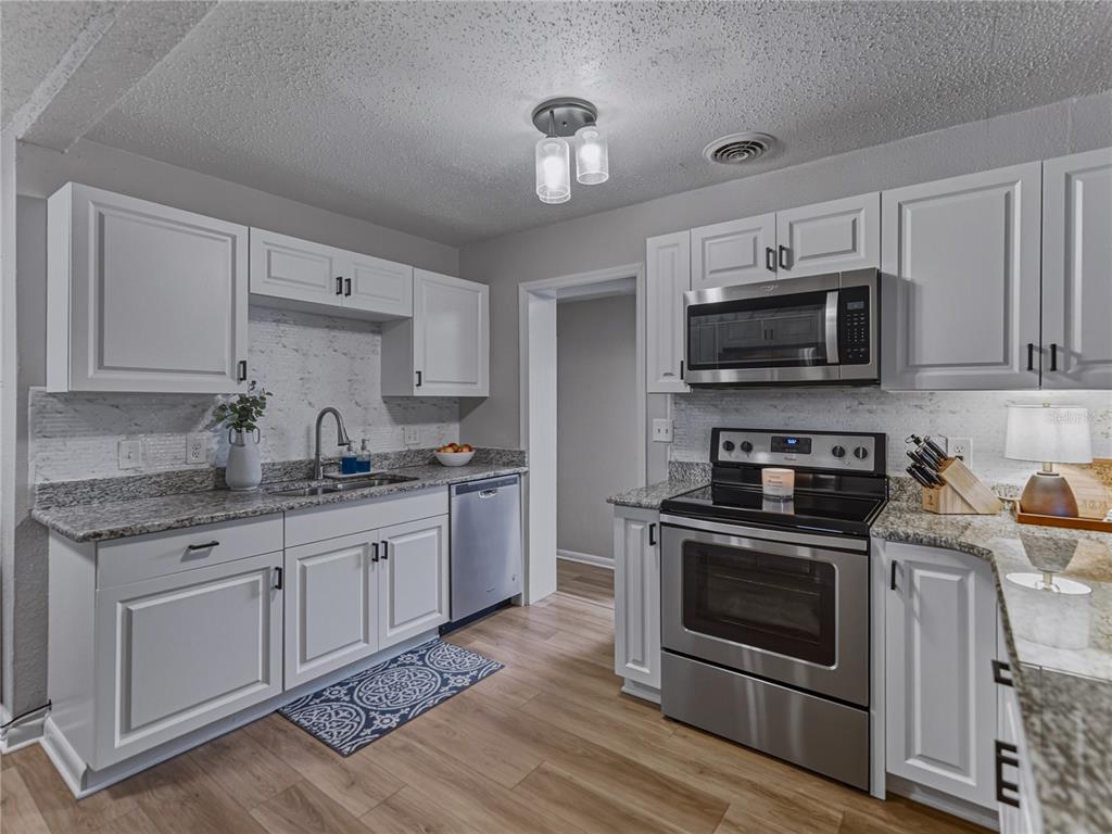 228 Azalea Street Lakeland, FL 33803 - Photo 22 of 80 a kitchen with stainless steel appliances granite countertop a stove top oven microwave and cabinets