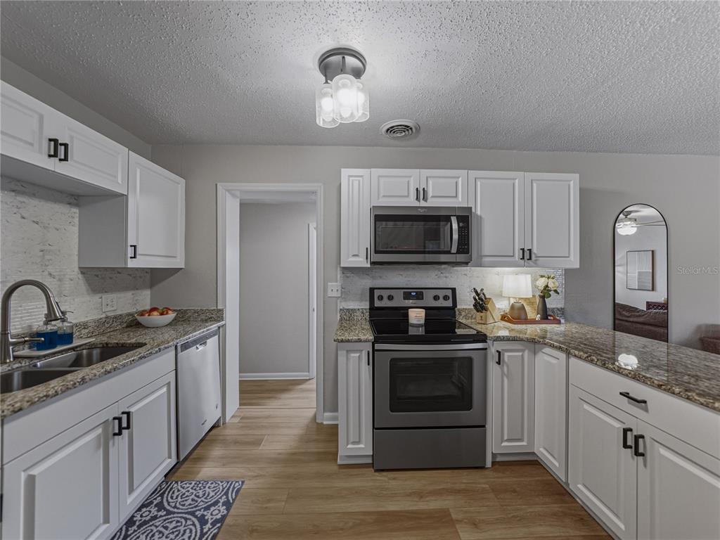228 Azalea Street Lakeland, FL 33803 - Photo 23 of 80 a kitchen with stainless steel appliances granite countertop a stove top oven a sink a refrigerator and cabinets