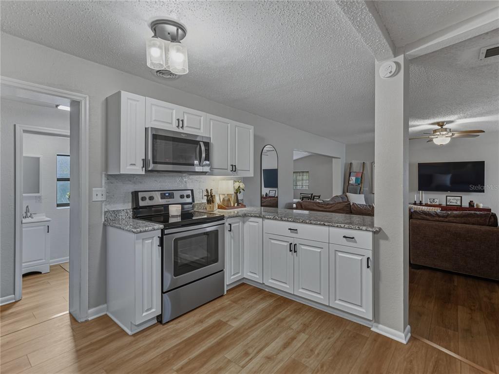 228 Azalea Street Lakeland, FL 33803 - Photo 24 of 80 a kitchen with stainless steel appliances granite countertop a stove top oven a refrigerator a sink and dishwasher with wooden floor