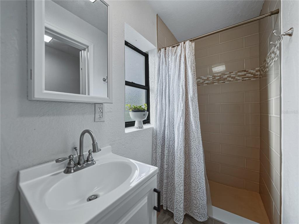 228 Azalea Street Lakeland, FL 33803 - Photo 37 of 80 a bathroom with a sink a mirror a window and a shower
