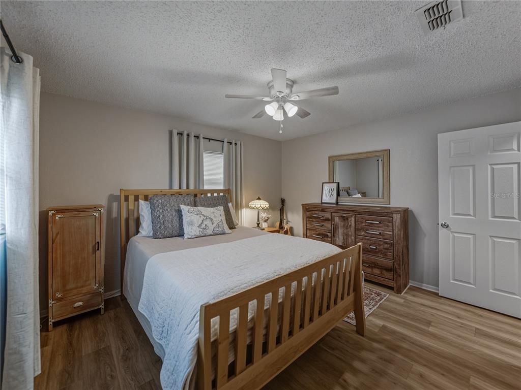 228 Azalea Street Lakeland, FL 33803 - Photo 43 of 80 a bedroom with a bed a chandelier and dresser