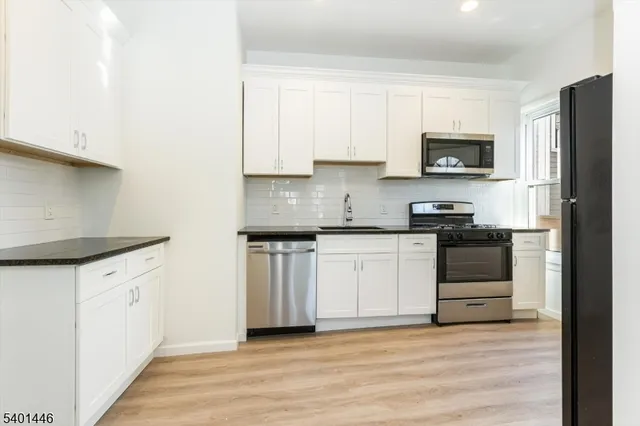a kitchen with granite countertop white cabinets and black stainless steel appliances