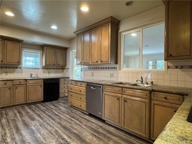 a kitchen with stainless steel appliances granite countertop wooden cabinets a sink and dishwasher a stove with wooden floor