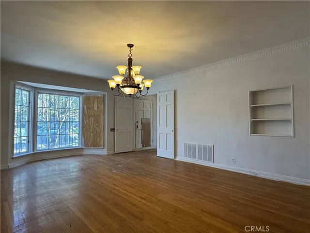 a view of an empty room with a window and wooden floor