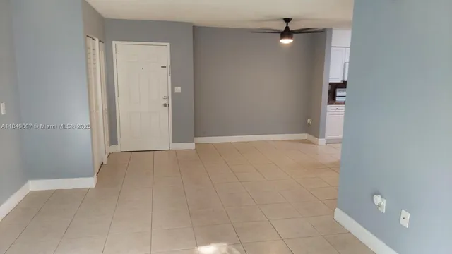 an empty room with an entryway and chandelier fan