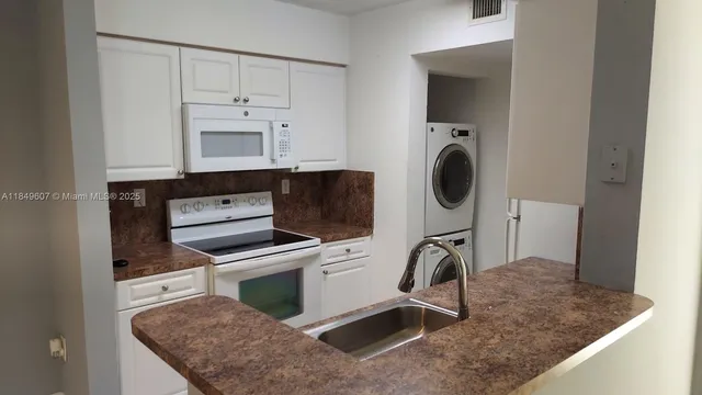 a kitchen with granite countertop a stove a sink and a microwave