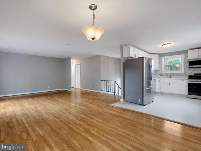 a view of a kitchen with a fridge and wooden floor