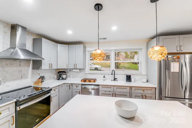 a kitchen with stainless steel appliances a stove a sink a oven a kitchen island a stove and a cabinets