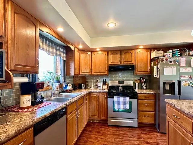 a kitchen with stainless steel appliances granite countertop a stove a sink and a refrigerator