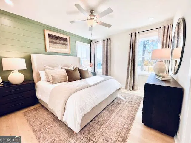 a bedroom with a bed lamp and a large mirror with wooden floor