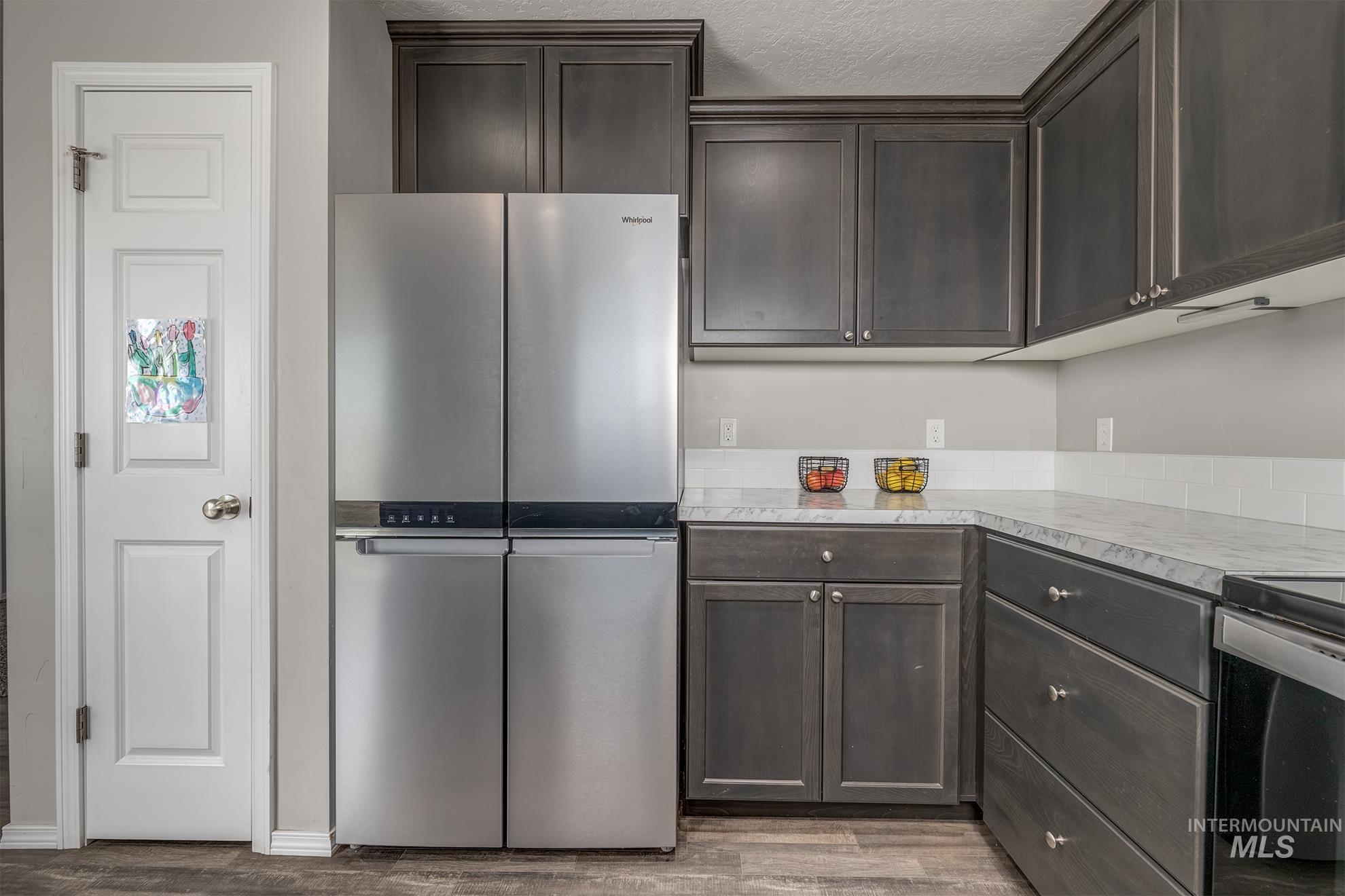 1049 Price Road Weiser, ID 83672 - Photo 11 of 47 Kitchen featuring dark wood-finish cabinetry, stainless steel appliances, light-toned countertops, and a white subway tile backsplash