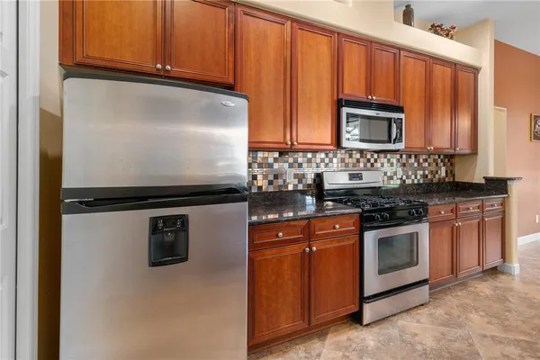 a kitchen with stainless steel appliances granite countertop a stove a sink and a microwave