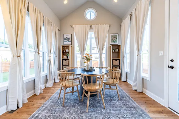 a kitchen with stainless steel appliances granite countertop a stove top oven a sink a dining table and chairs with wooden floor