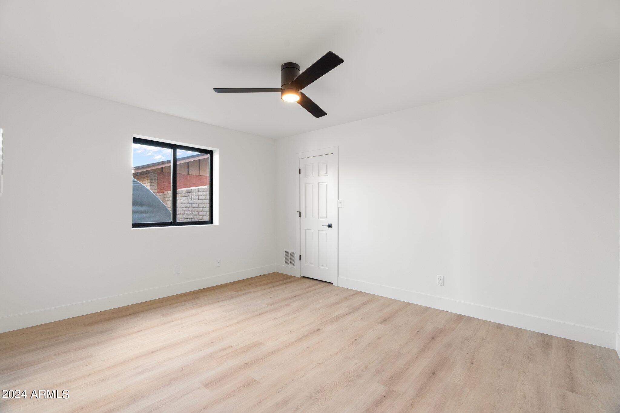 1643 West Griswold Road Phoenix, AZ 85021 - Photo 27 of 81 an empty room with wooden floor ceiling fan and windows