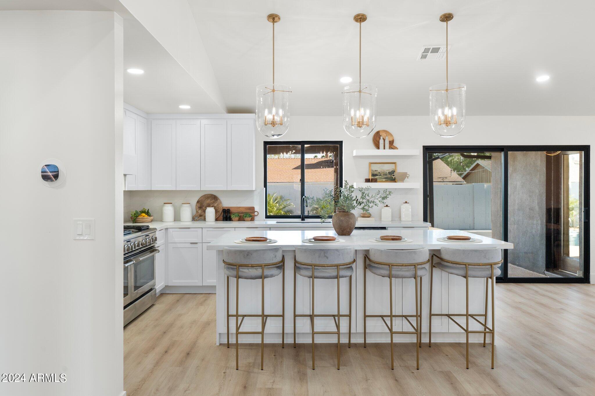 1643 West Griswold Road Phoenix, AZ 85021 - Photo 53 of 81 a kitchen with stainless steel appliances granite countertop a stove a sink and white cabinets with wooden floor
