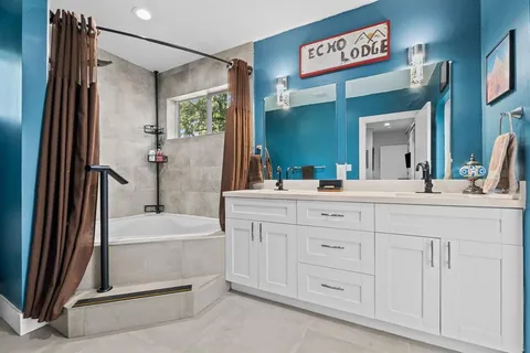 a bathroom with a double vanity sink a mirror and a bathtub