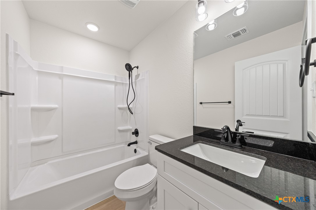 1204 Martin Luther King Jr Lane, Unit A Temple, TX 76504 - Photo 16 of 21 a bathroom with a granite countertop sink a toilet a mirror and shower
