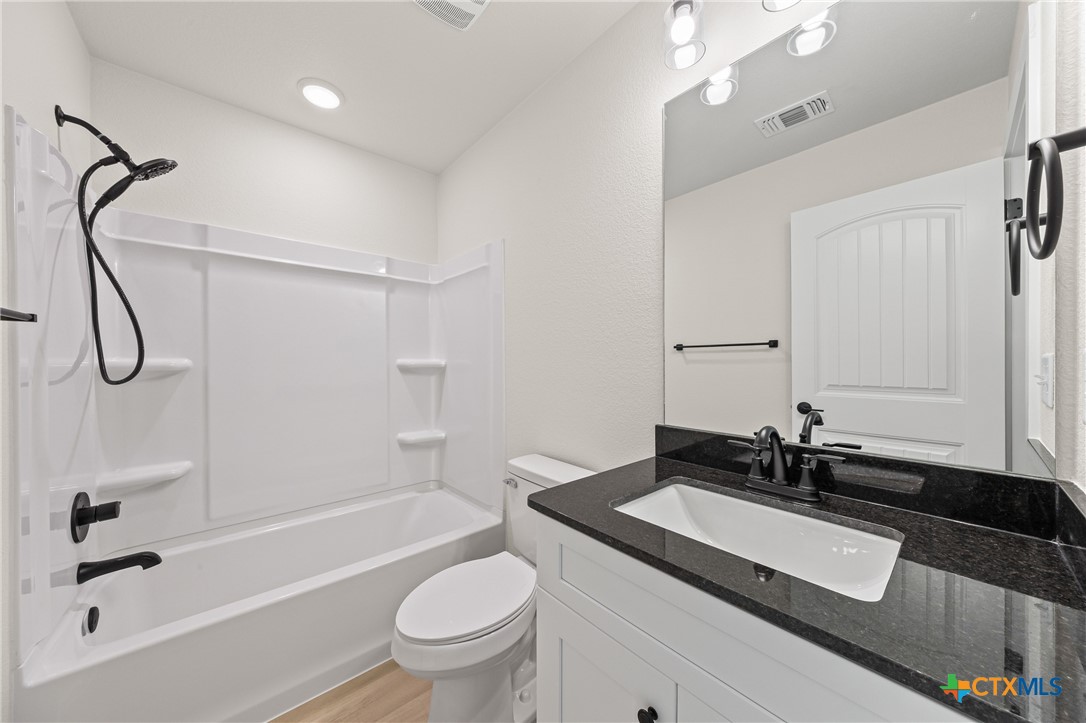 1204 Martin Luther King Jr Lane, Unit A Temple, TX 76504 - Photo 19 of 21 a bathroom with a granite countertop sink a toilet and a bathtub