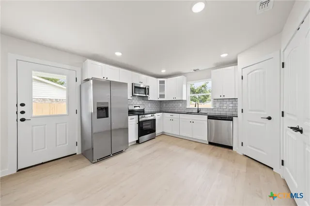 a kitchen with granite countertop white cabinets white stainless steel appliances and a sink