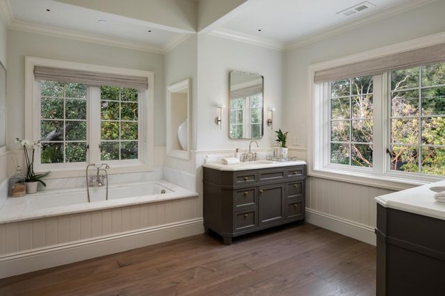 a bathroom with a double vanity sink bathtub and window