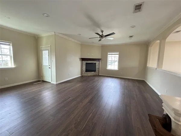 an empty room with wooden floor fireplace and windows