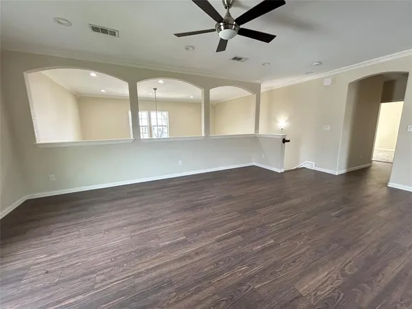 a view of an empty room with a kitchen and a window