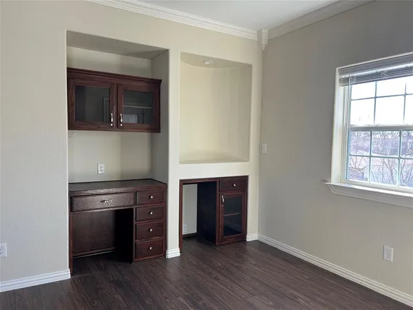 an empty room with wooden floor a ceiling fan and windows