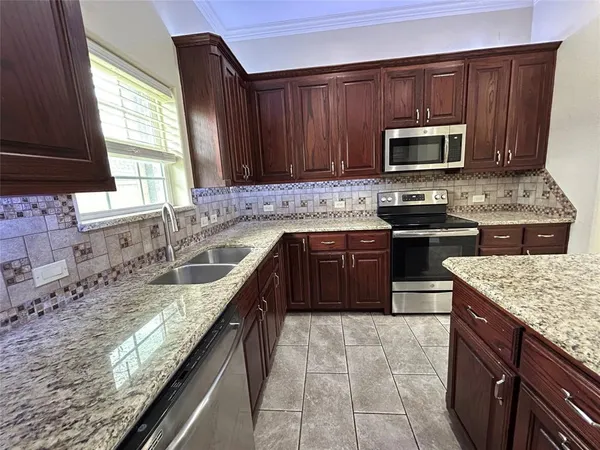 a kitchen with stainless steel appliances granite countertop wooden cabinets stove top oven and sink