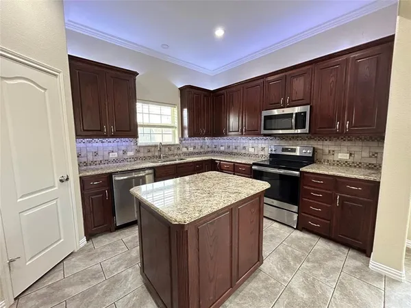 a kitchen with stainless steel appliances granite countertop wooden cabinets a stove top oven a sink and dishwasher