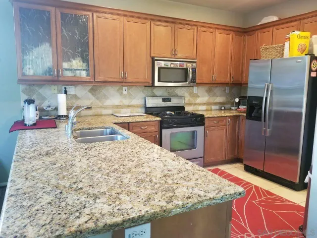a kitchen with stainless steel appliances granite countertop a refrigerator sink and stove