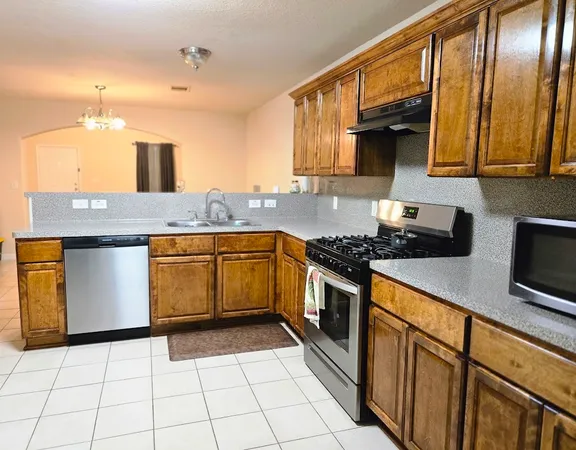 a kitchen with stainless steel appliances granite countertop a stove a sink and a microwave
