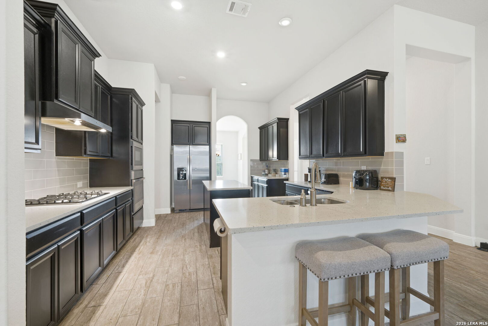 32103 Mirasol Bend Bulverde, TX 78163 - Photo 11 of 23 a kitchen with stainless steel appliances granite countertop a stove top oven a sink dishwasher a dining table and chairs with wooden floor