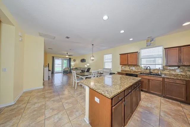 a kitchen with kitchen island granite countertop a sink stove and cabinets