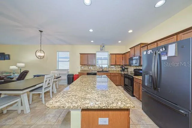 a kitchen with stainless steel appliances granite countertop sink stove refrigerator and cabinets