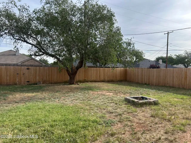a backyard with table and chairs and wooden fence