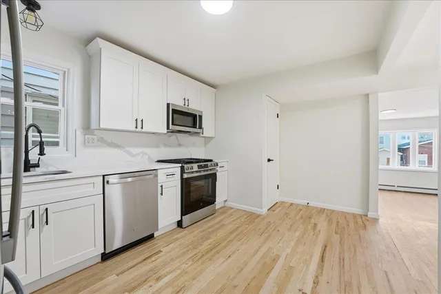 a kitchen with granite countertop white cabinets and stainless steel appliances