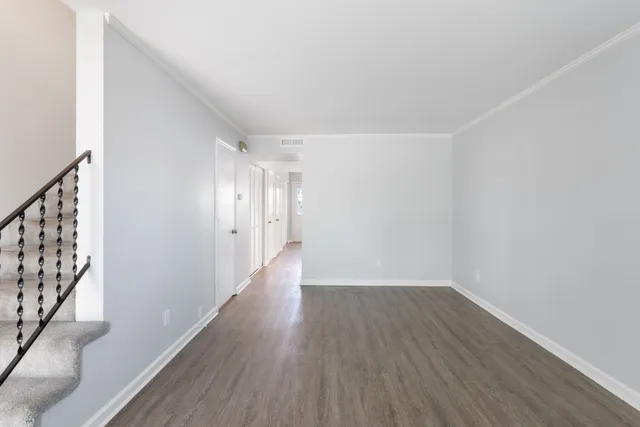 a view of an empty room with wooden floor and stairs